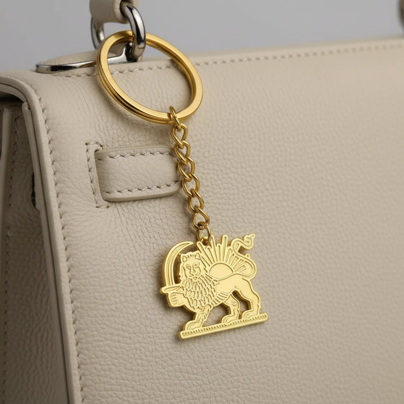 Gold keychain with lion emblem and measurement label on a white background