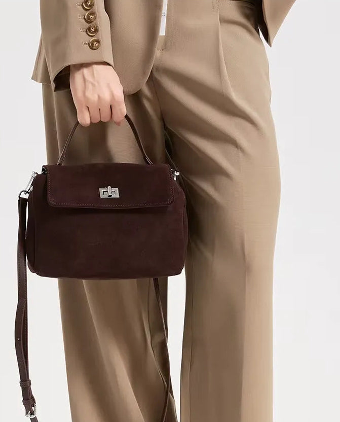Person holding a brown handbag with a plain background