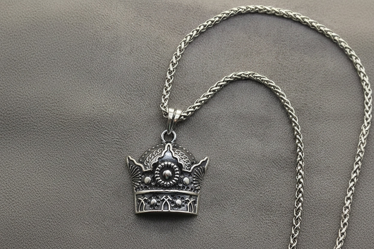 Silver crown pendant necklace on a gray background