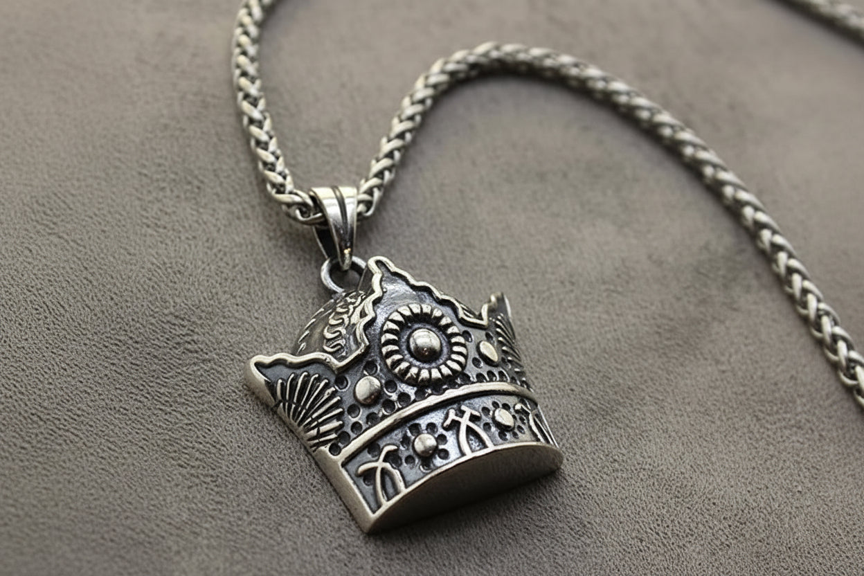 Silver crown pendant necklace on a gray surface