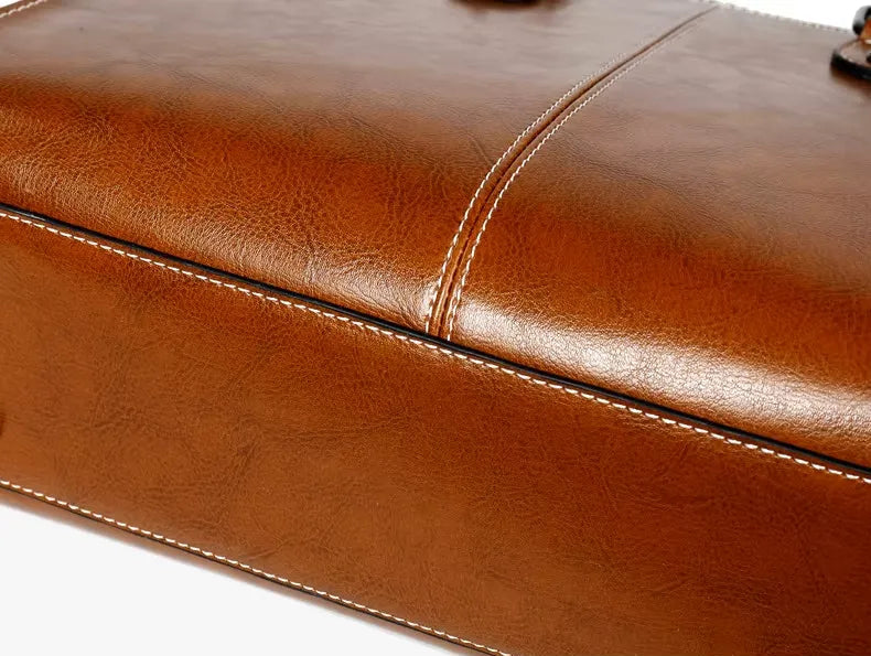 Close-up of a brown leather bag with visible stitching on a white background