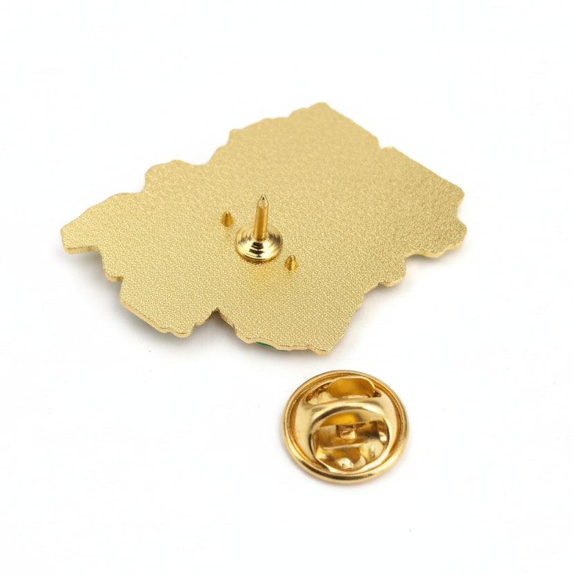 Gold-colored pin with a unique design on a white background