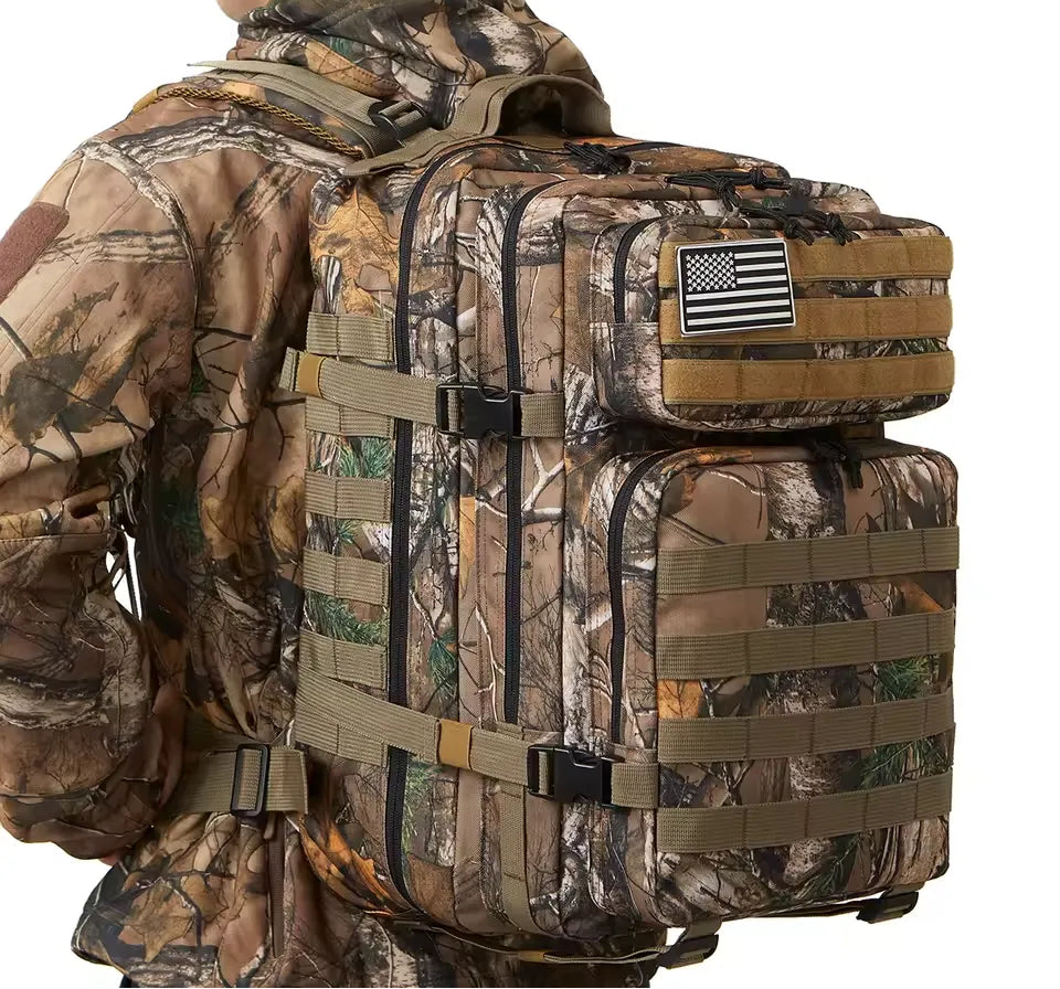 Camouflage backpack with American flag patch worn by a person in camouflage gear.