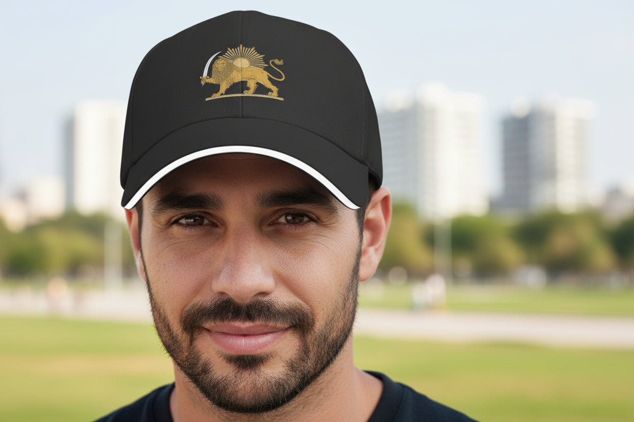 Man wearing a black cap with a gold emblem in an outdoor setting