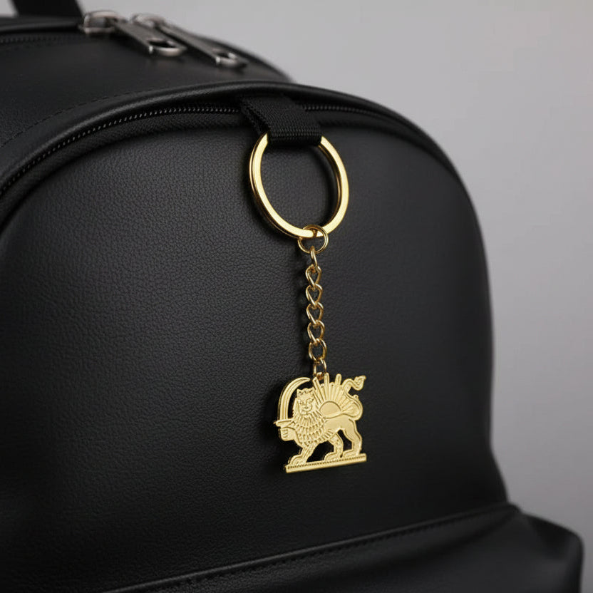 Gold keychain with lion emblem and measurement label on a white background
